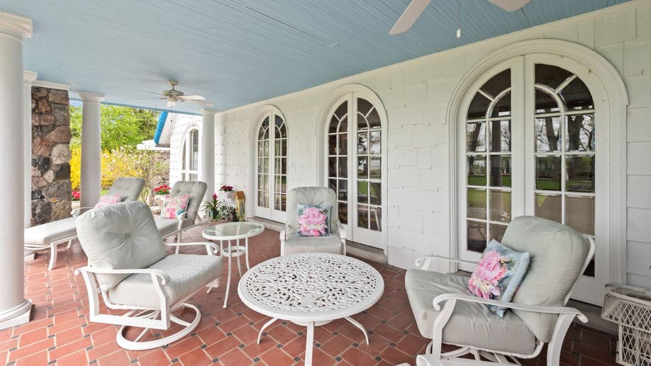 The Smurf House has a blue-roofed porch and arched window. There's a dining and side table with four chairs.