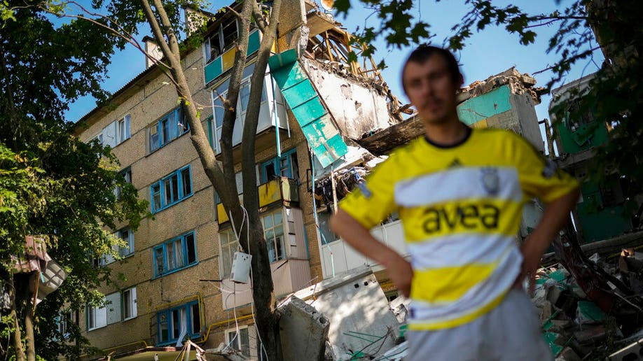 Ukrainian stands near to heavily damaged building