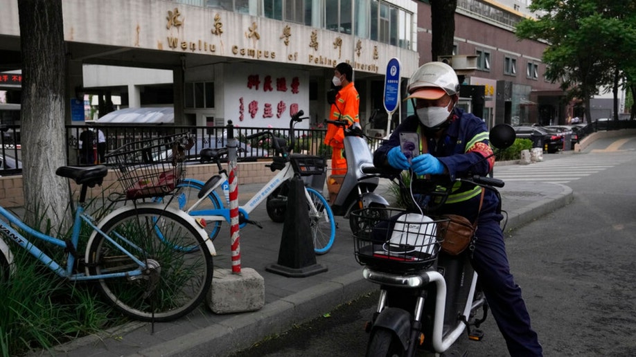 Workers stand near an entrance to the Wanliu Campus of Beijing's Peking University