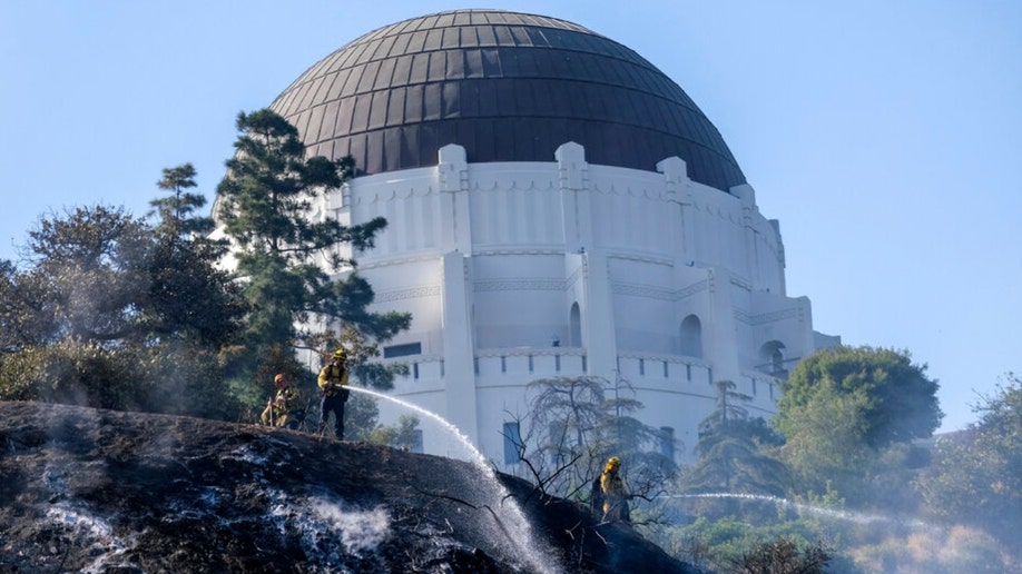 Firefighters spray water on hot spots during a brushfire near Los Angeles' Griffith Observatory