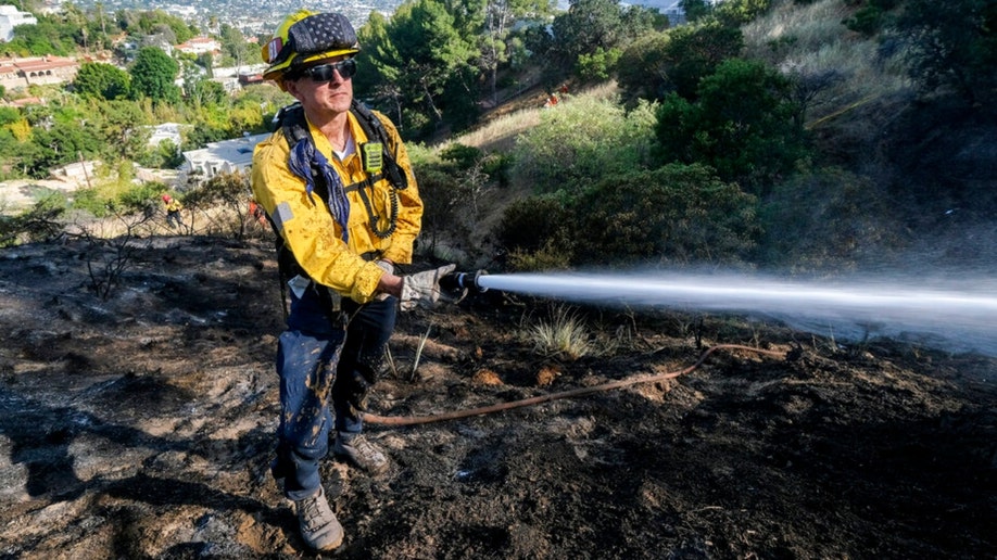 A firefighter works on a brushfire near Los Angeles' Griffith Observatory