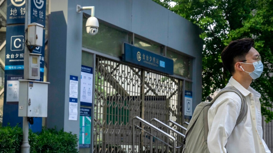 A commuter wearing a face mask walks by a Beijing subway station