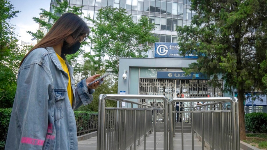 A commuter wearing a face mask walks by a Beijing subway station