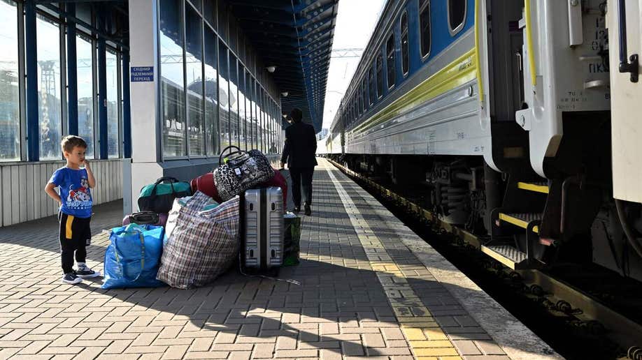 A child stands near luggage as a parent disembarks with other bags, as some women and children, some of the thousands who fled the Ukraine after Russia invaded, arrive from Poland,