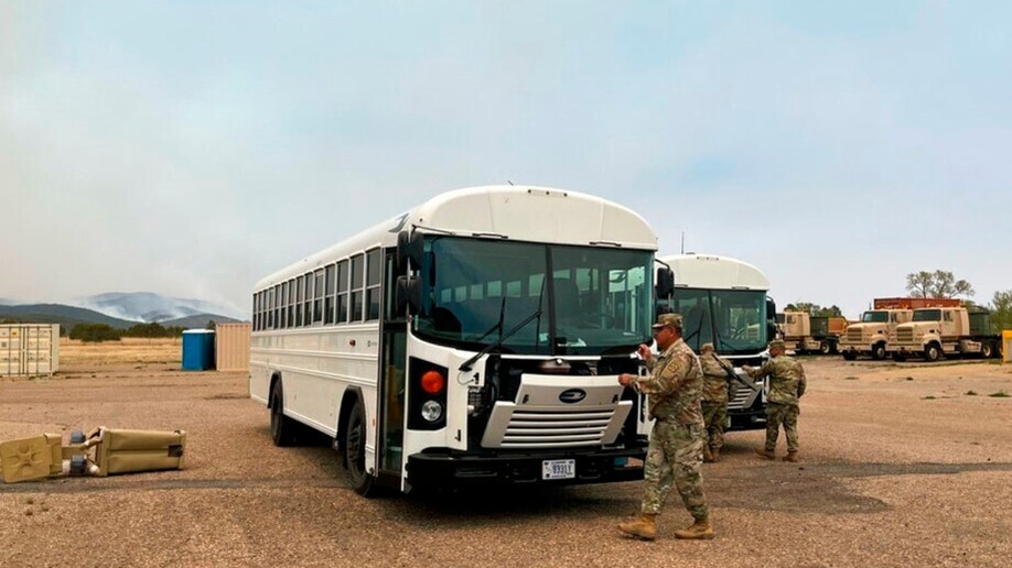New Mexico National Guard soldiers on the ground ready buses to transport evacuees