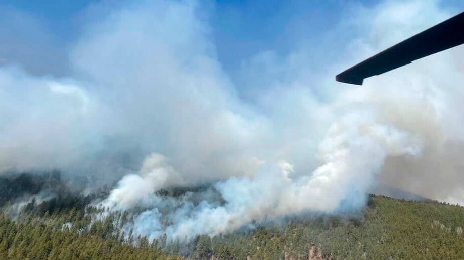 A New Mexico National Guard Aviation UH-60 Black Hawk drops thousands of gallons of water