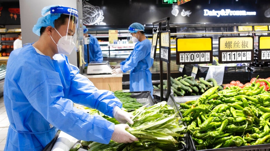 Workers prepare the sale of vegetables at a supermarket in Xuhui District of eastern China's Shanghai