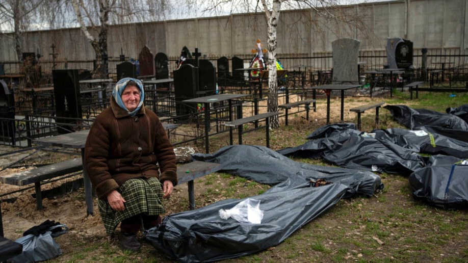 A woman sits next to the bodies of Bucha soldiers