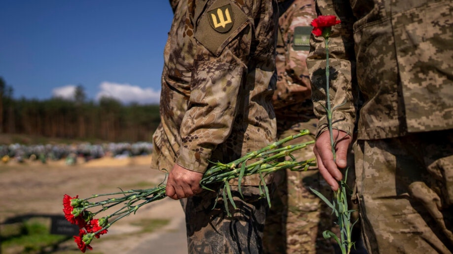 Irpin Territorial Defence and Ukrainian Army soldiers hold flowers