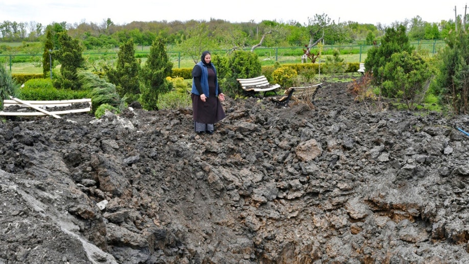 Sister Evdokia gestures in front of a crater 