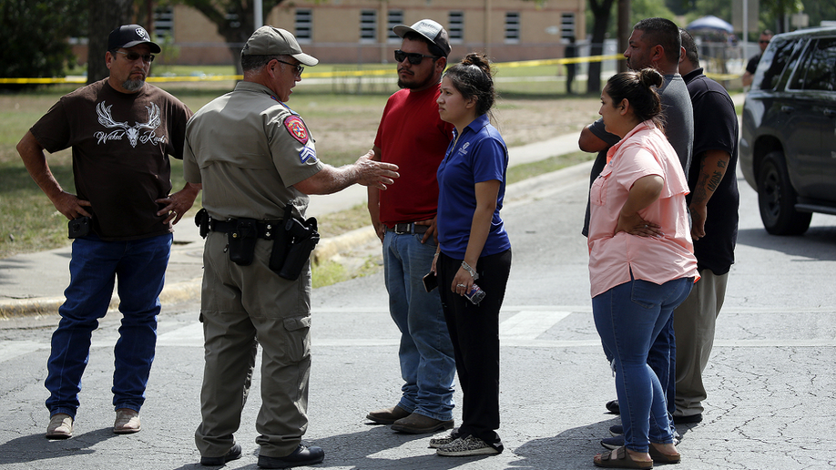 A police officer talks to people outside Robb Elementary School in Uvalde, Texas