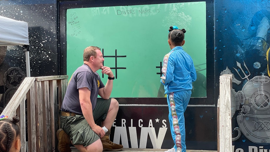 navy diver kneels with kid in times square