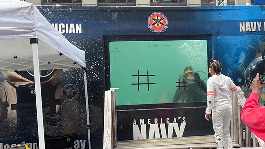 us navy diver waves from tank in times square