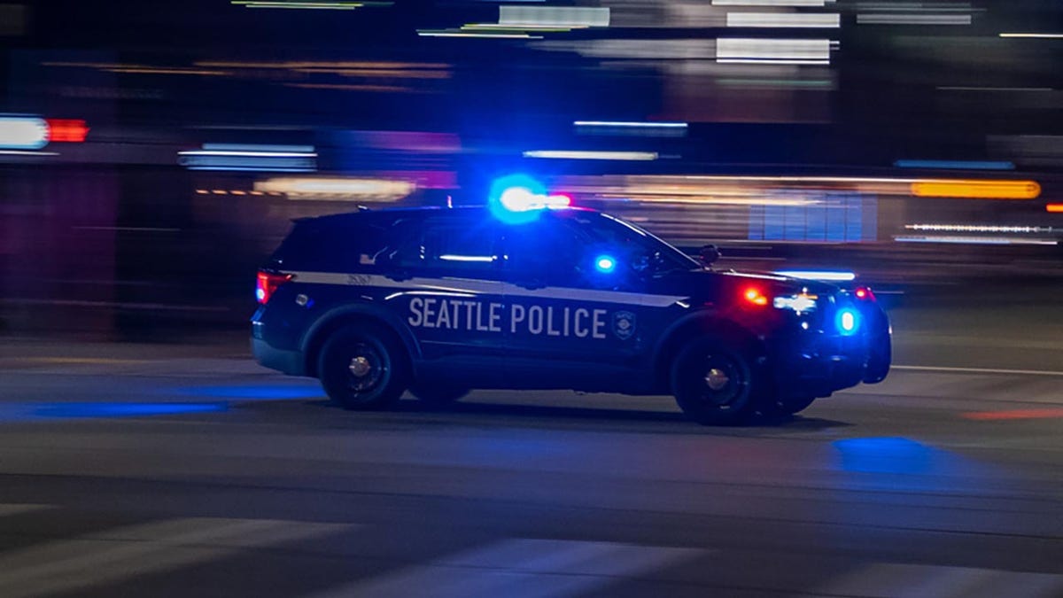 Seattle Police car with lights on seen driving down road