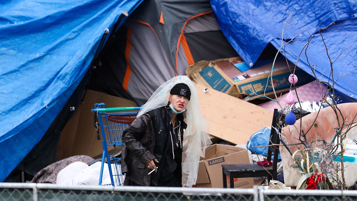 Homeless woman wears veil by tent encampment