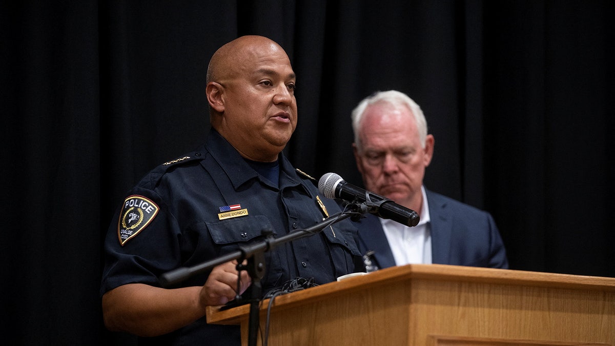 Uvalde police chief Pete Arredondo speaks at a podium in a black police uniform