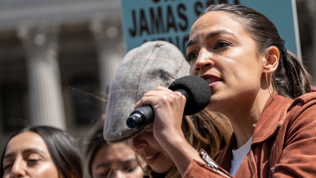 Alexandria Ocasio-Cortez speaking into a microphone