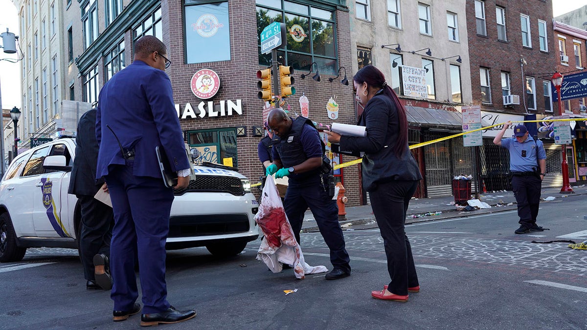 Philadelphia police officer hold blood soaked clothing after mass shooting