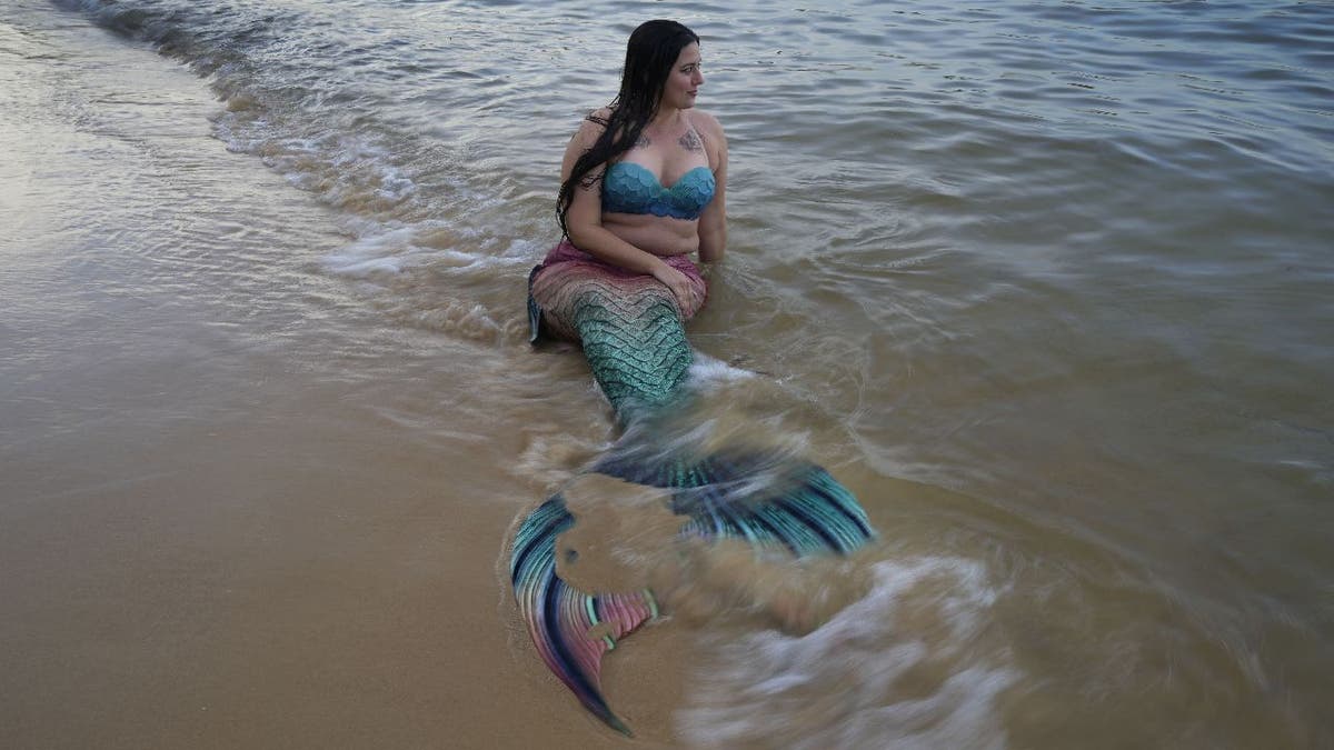 Lauren Metzler rests shoreside in her mermaid tail