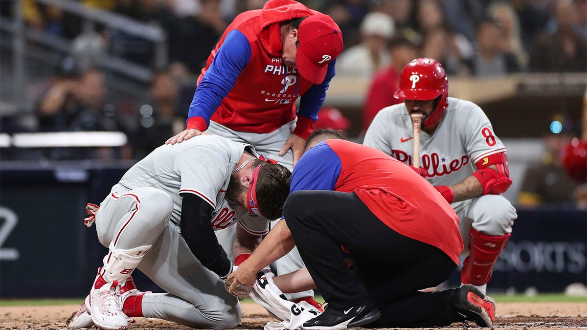 Bryce Harper is surrounded by athletic trainers on the ground