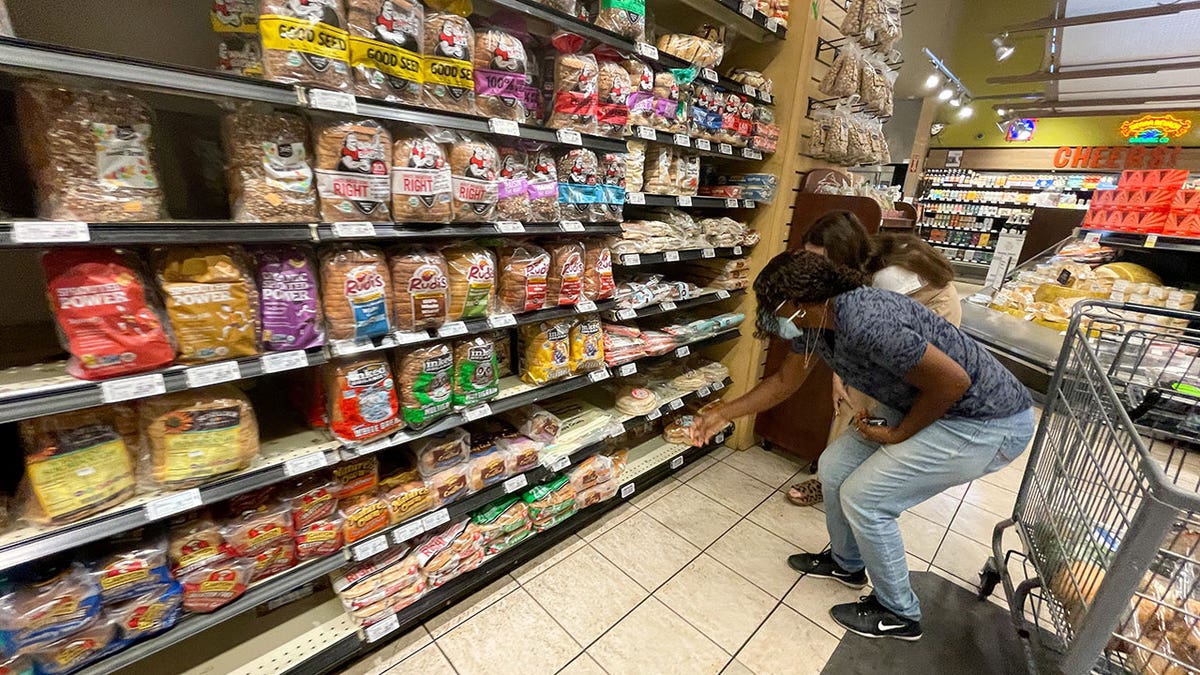 supermarket bread aisle with masked shoppers 
