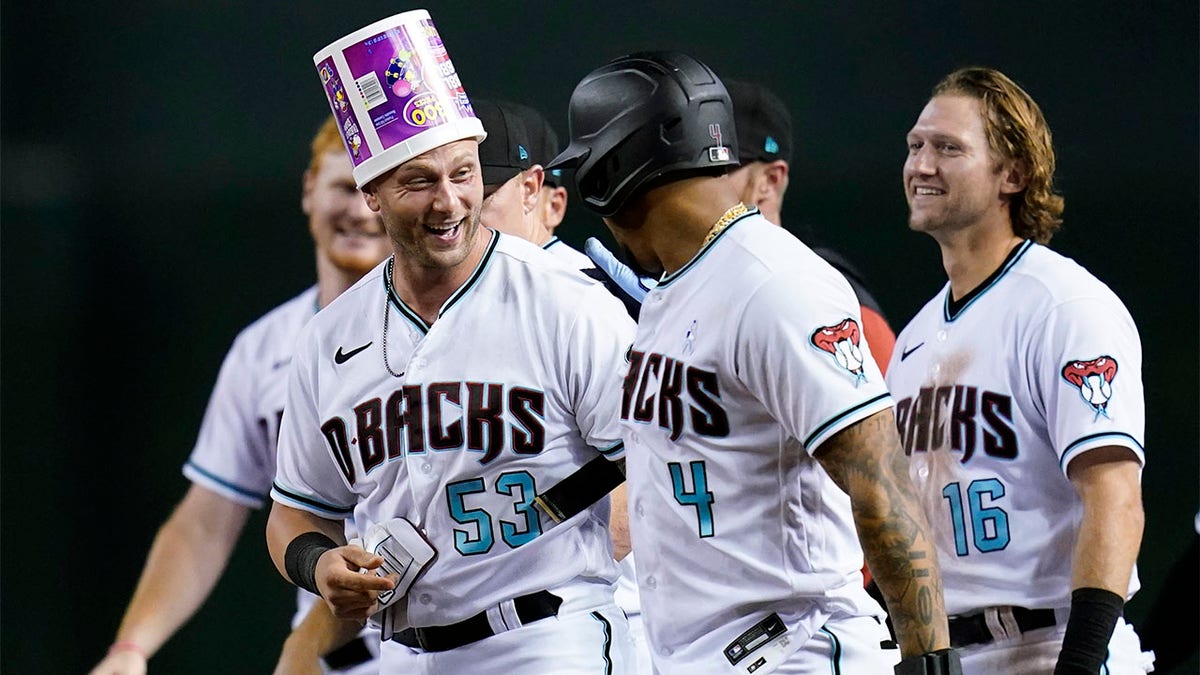 Christian Walker talks with Ketel Marie with a bucket on his head