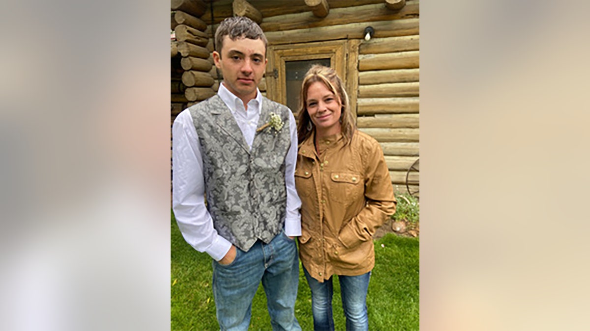 Dylan Rounds and Mom Candice Cooley pose outside log cabin