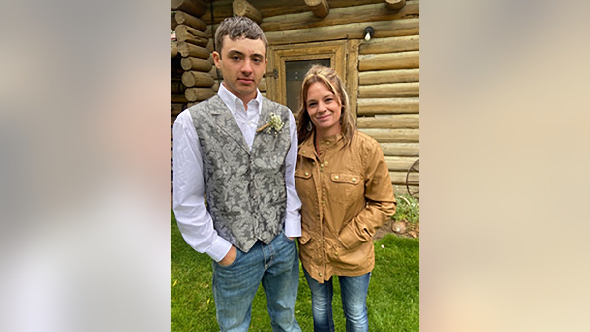 Dylan Rounds and Mom pose outside log cabin