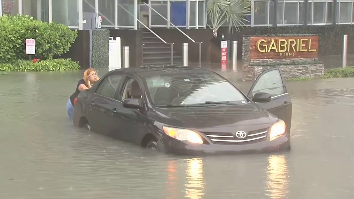 Woman pushes car caught in water in Miami