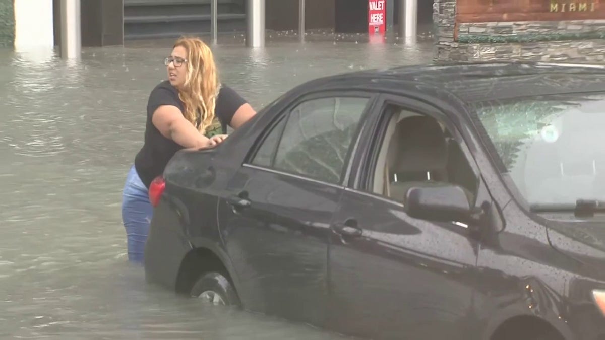 Woman pushes car caught in water in Miami