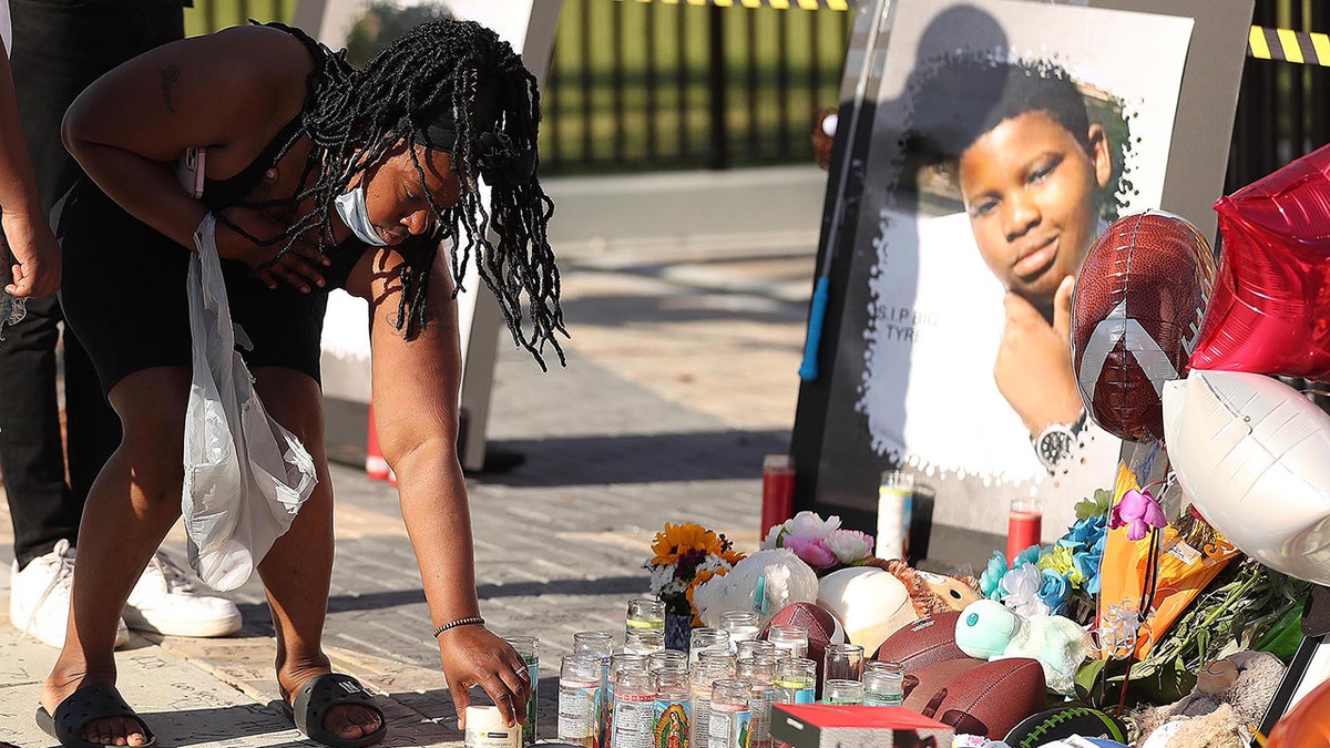 Woman places candle at Tyre Sampson memoria