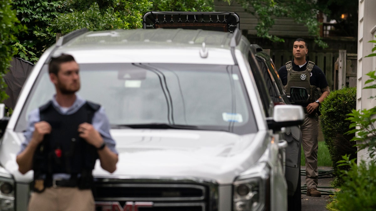 Law enforcement officers stand guard as protesters march past Supreme Court Justice Brett Kavanaugh's home