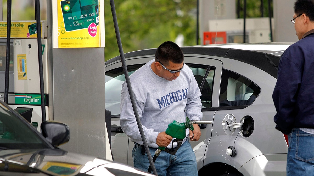 Man in Michigan sweatshirt pumps gas