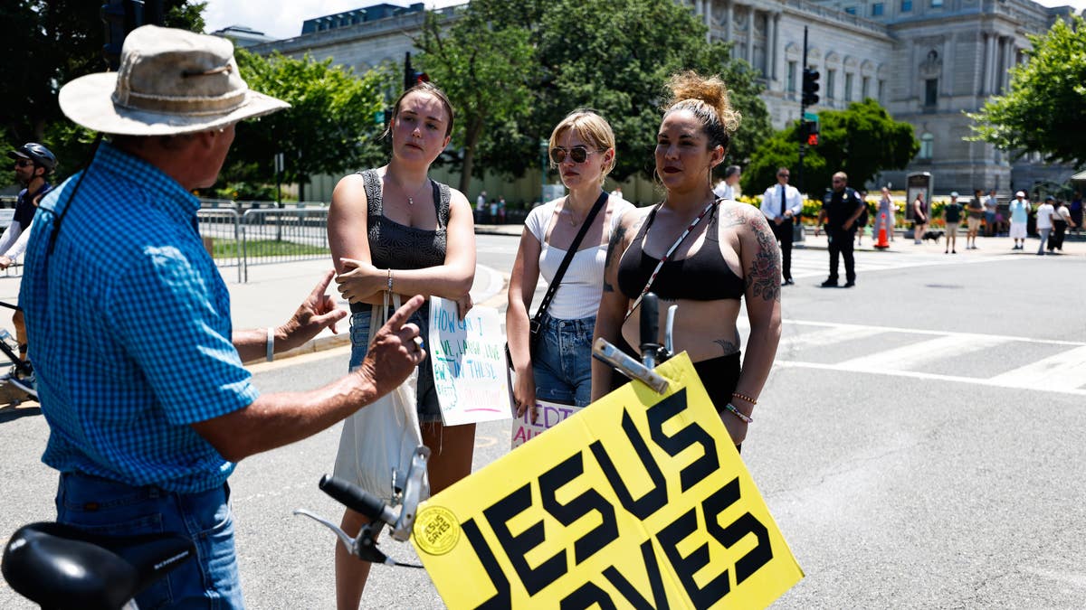 Three women hold a 'Jesus Saves' sign