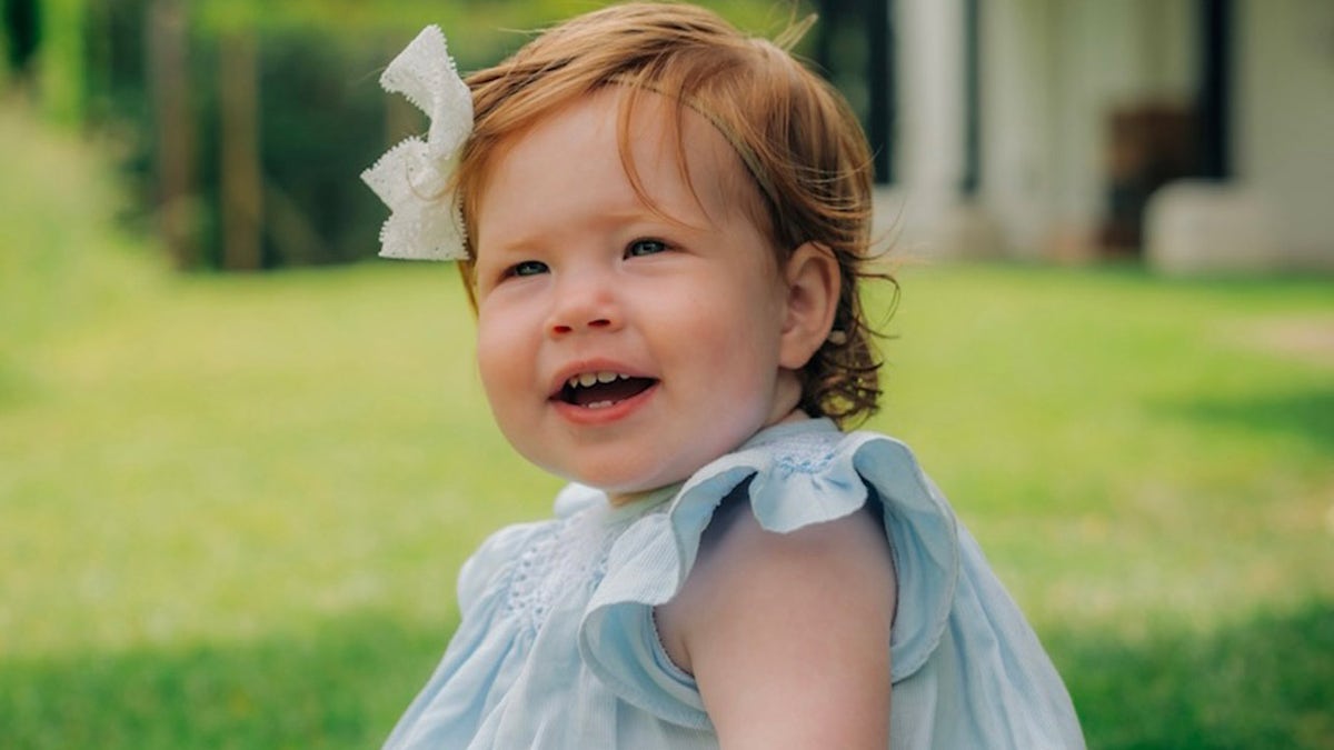 The Duke and Duchess of Sussex shared the first photo of daughter Lilibet smiling in a blue dress with a white bow in her bright red hair