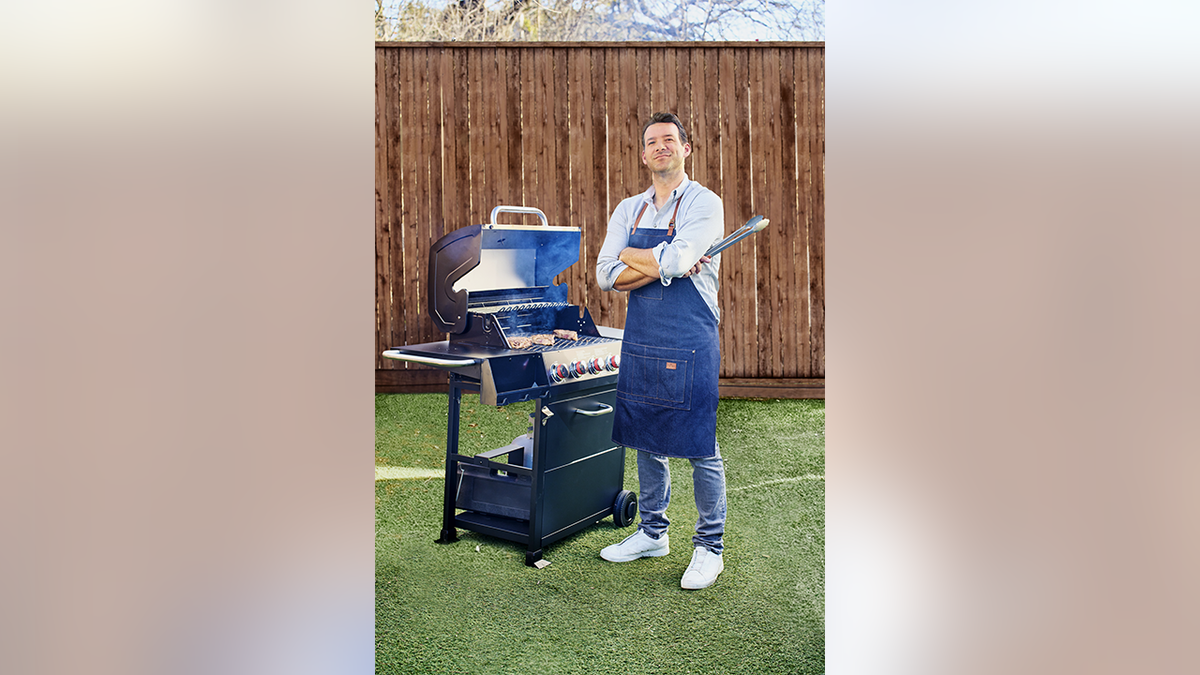 Tony Romo stands next to grill