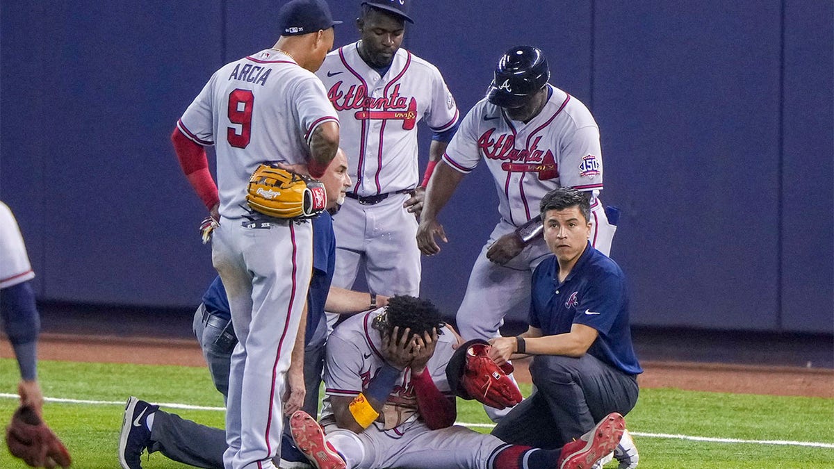 Ronald Acuña Jr. surrounded by teammates after suffering injury