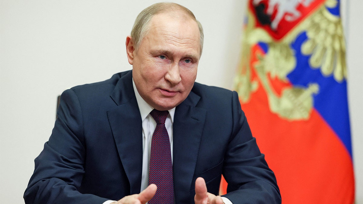 Russian President Vladimir Putin speaks to students wearing suit and tie in front of a Russian flag