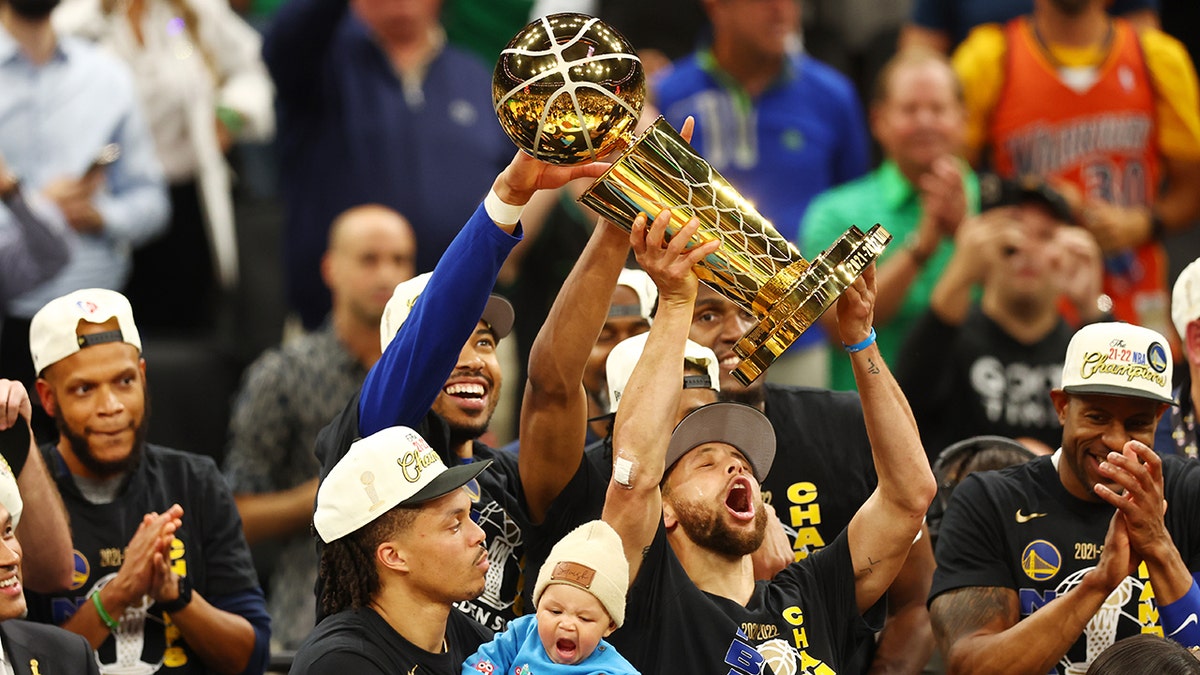 Stephen Curry raises the NBA trophy