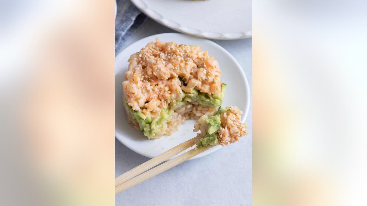 Sushi stack on plate being eaten with chopsticks