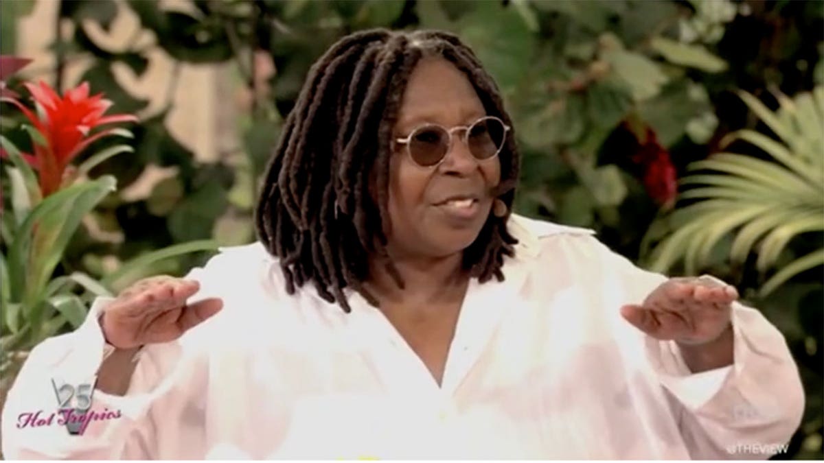 Whoopi Goldberg with her arms raised