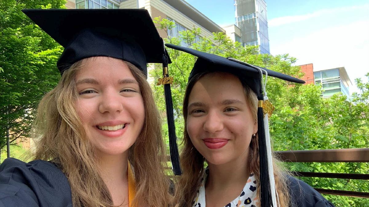 Alina and Anastasia Antropova pose in their graduation cap and gown