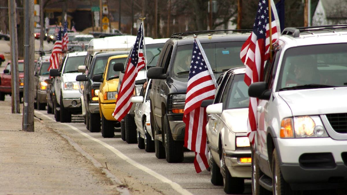 Cars drive on road with American flags up