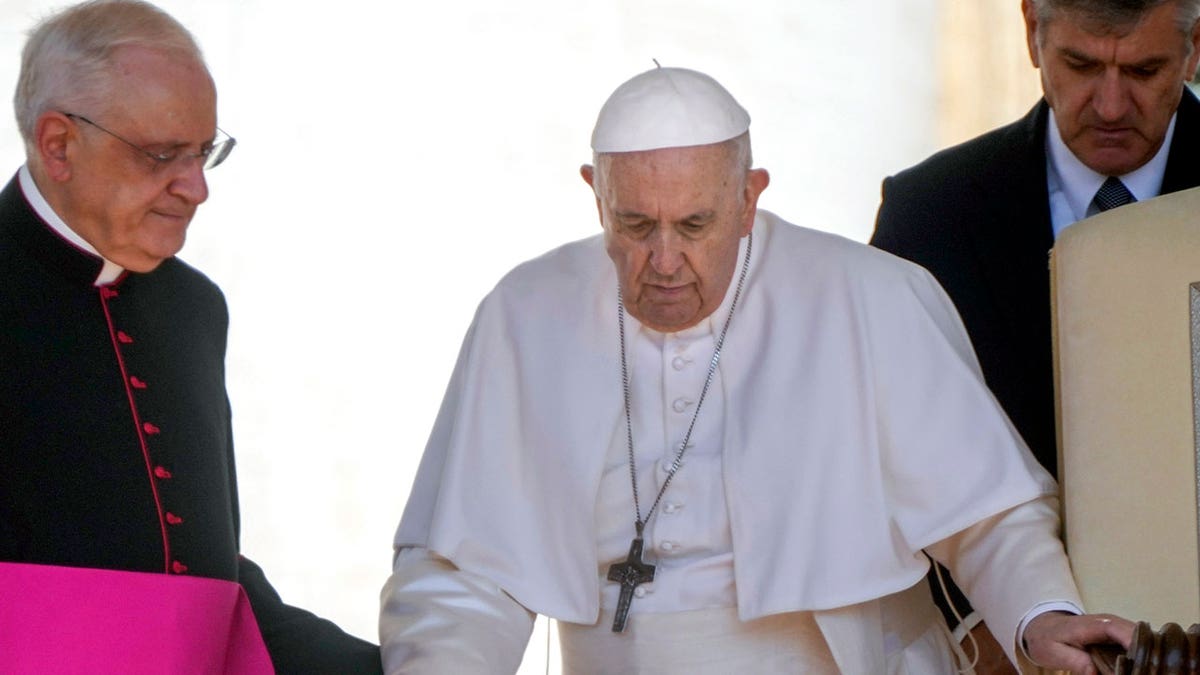Pope Francis helped by aide