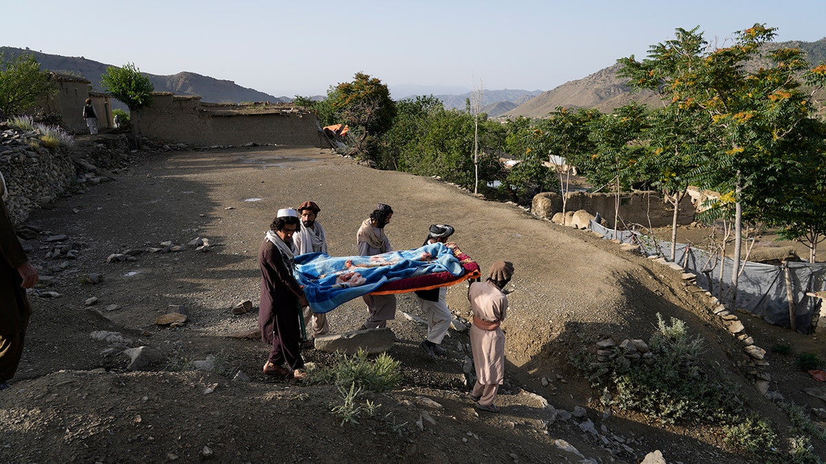 Afghan burial site after earthquake with people carrying a casket