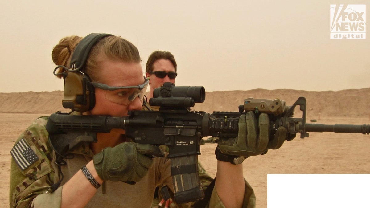 Female soldier aims rifle