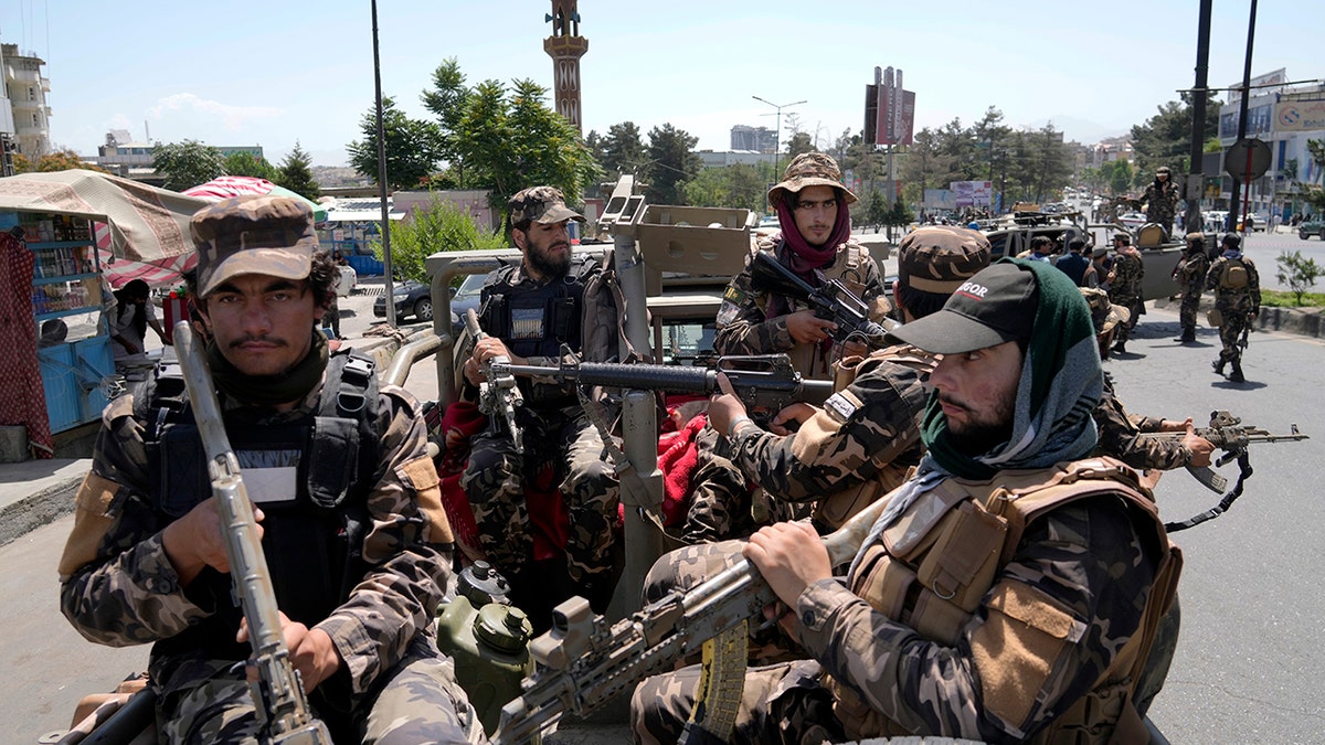 Taliban fighters guard explosion site dressed in miitary uniforms and holding weapons