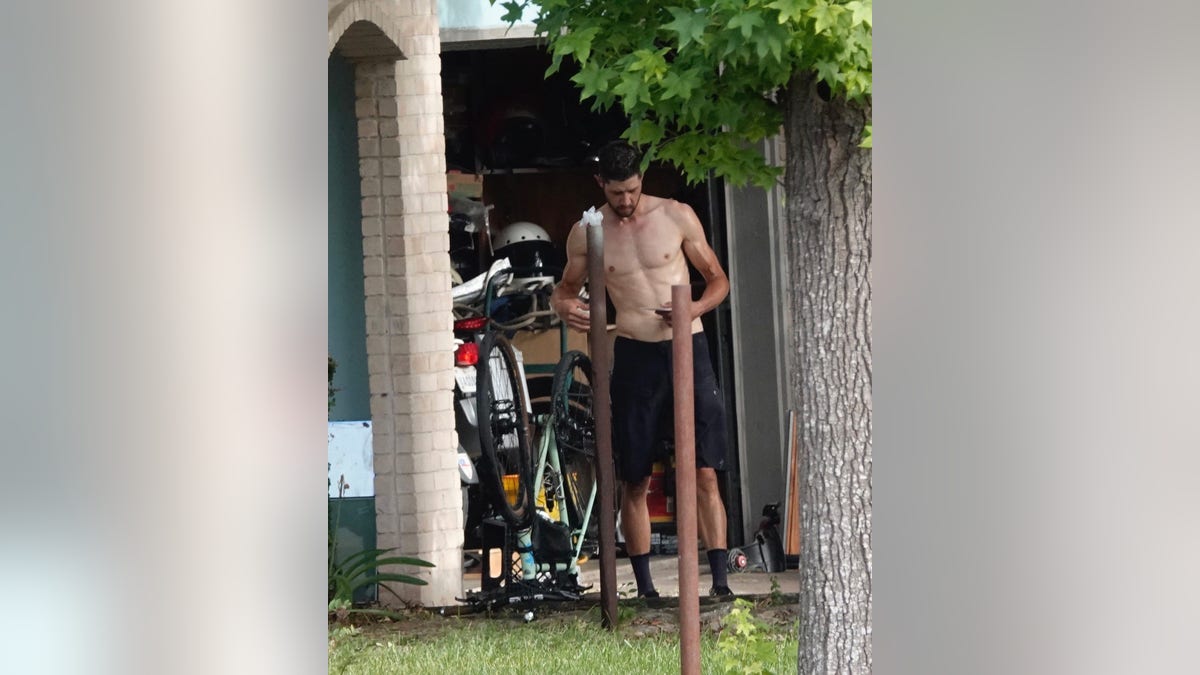 Colin Stricking shirtless in front of his garage