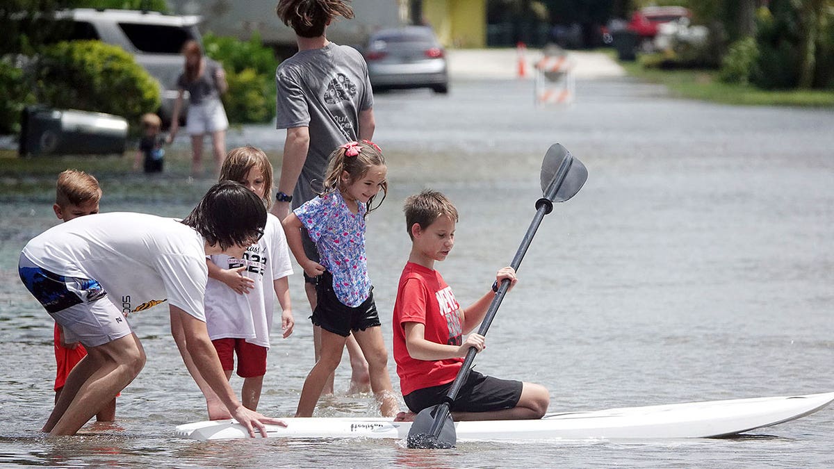 Boys paddle in street during Tropical Storm Alex