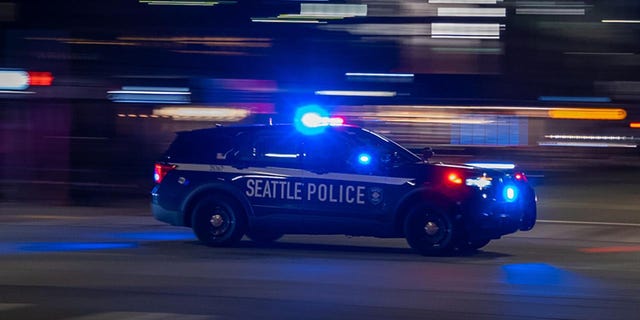 Seattle Police car with lights on seen driving down road